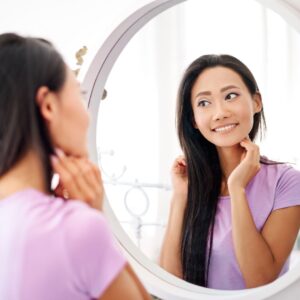 woman looking at face in the mirror